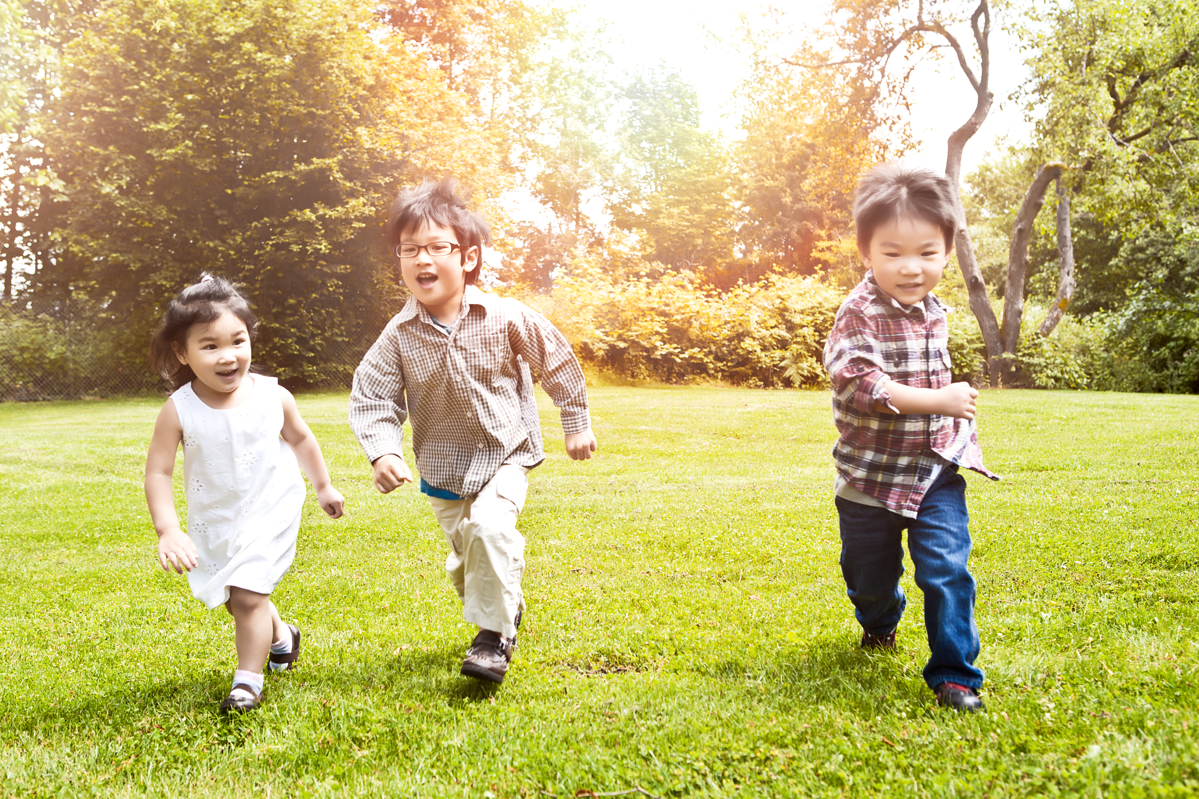 A shot of three Asian kids running in a park (focus in the middle kid)