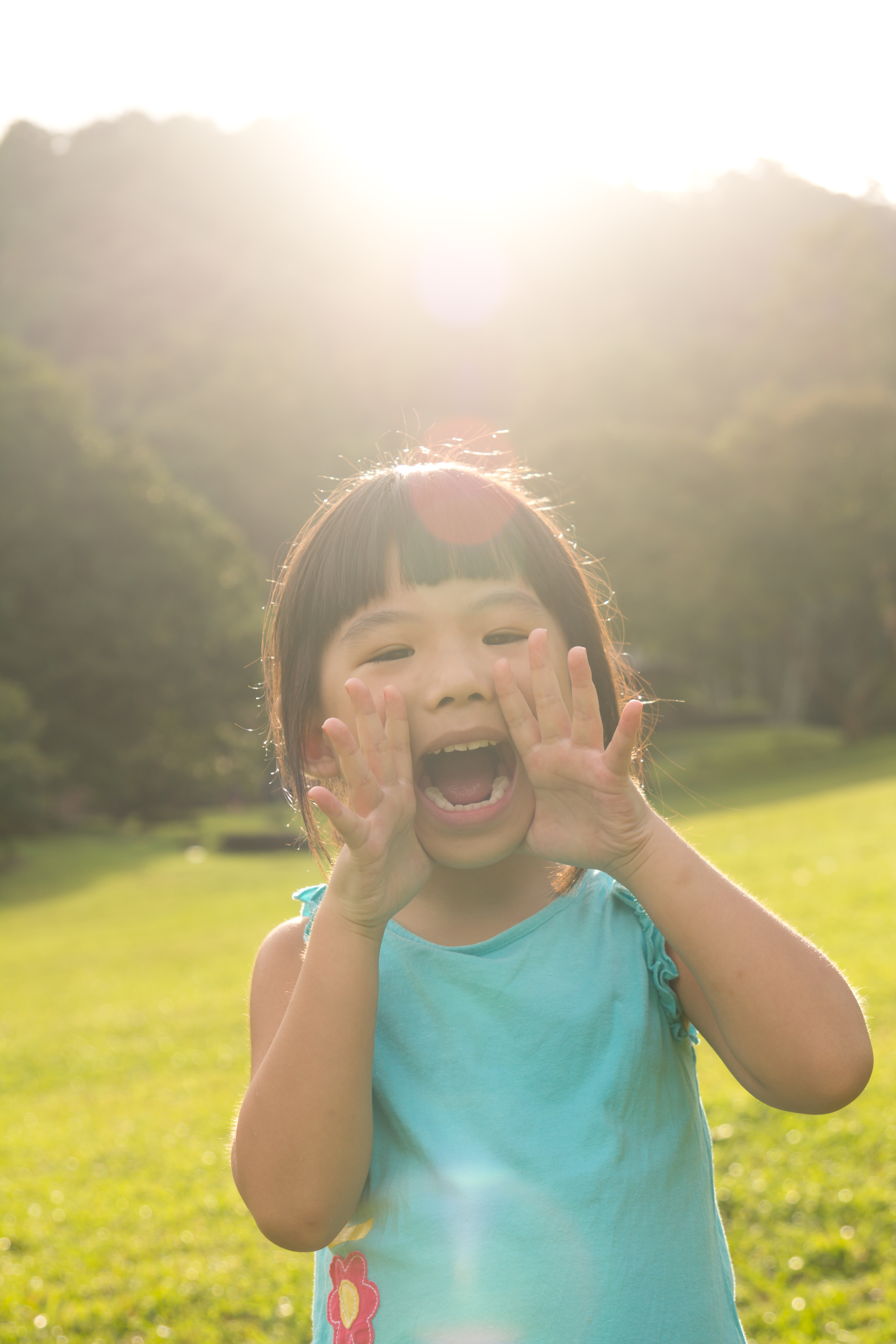 Asian child is shouting at park against sunlight