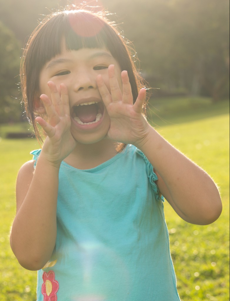 Asian child is shouting at park against sunlight