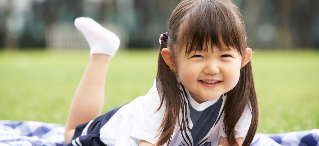 Young Chinese Girl Lying On Blanket In Park