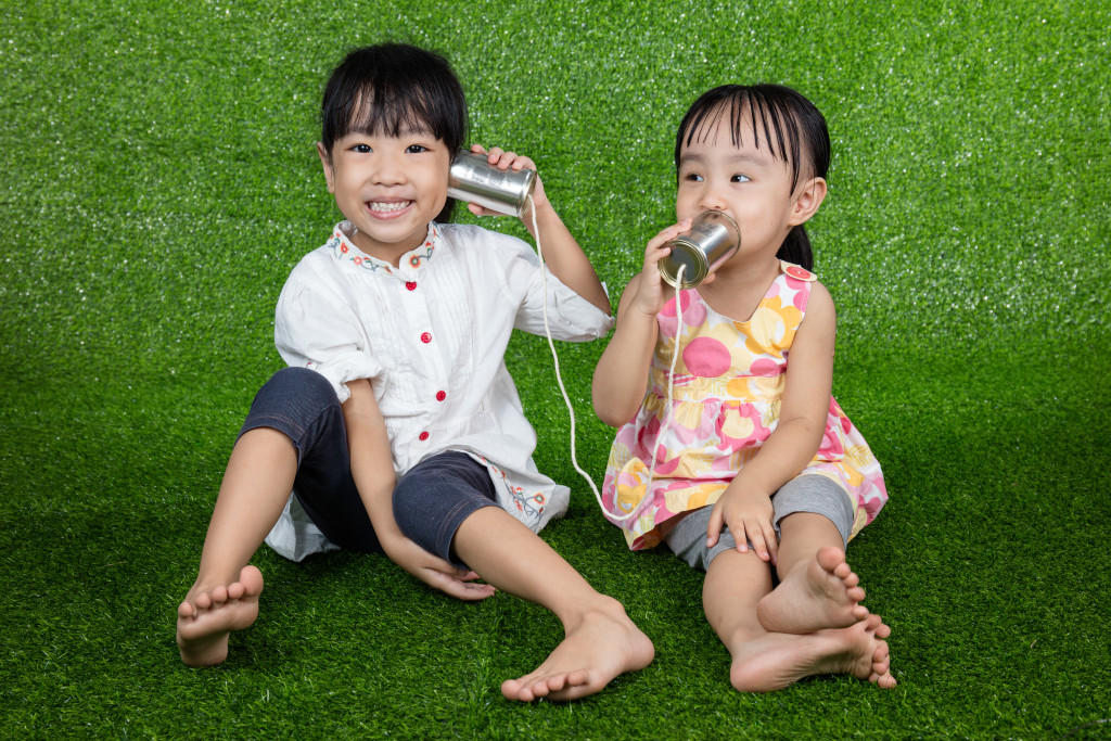 Asian Chinese Kids Playing with Tin Can Phone on green grass
