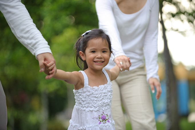 Little girl smiling in the park while with parents