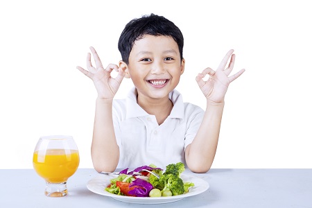 Cute boy making OK gesture while having salad, isolated on white
