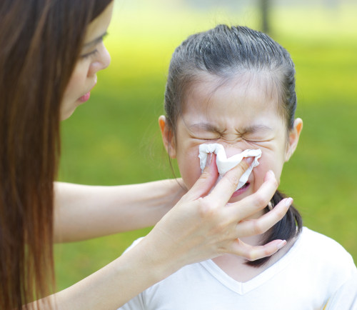 Cute little Asian girl with the flu, outdoor park